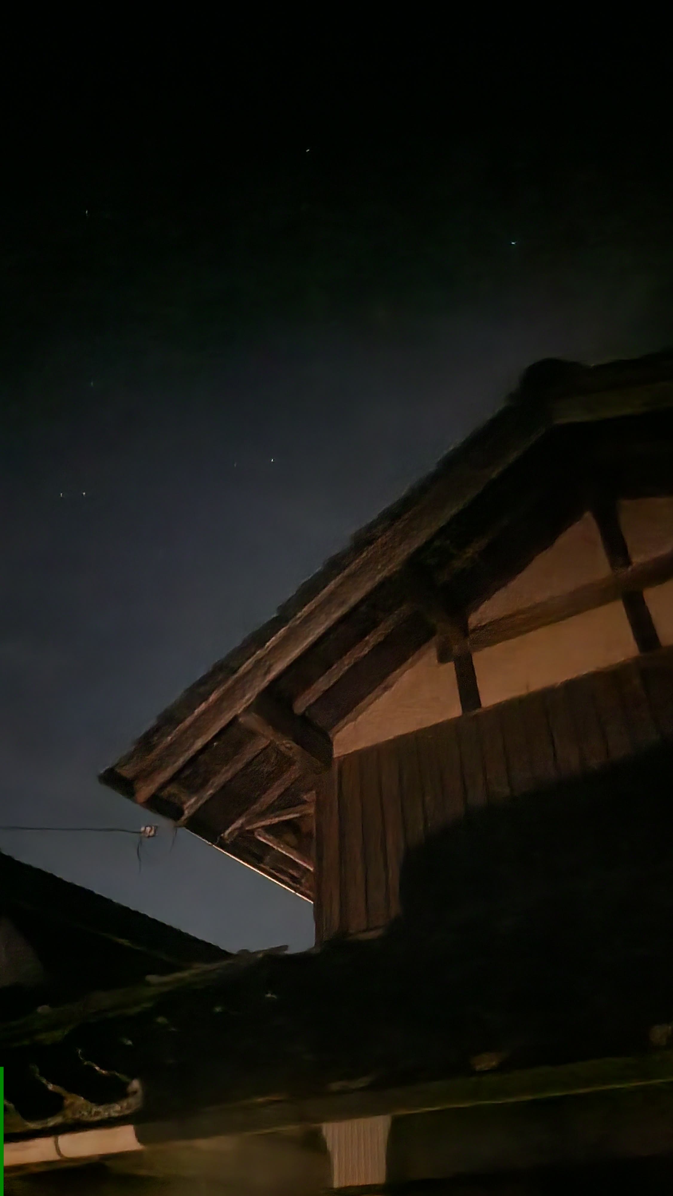 暗い夜空を背景に浮かぶ古い木の軒
