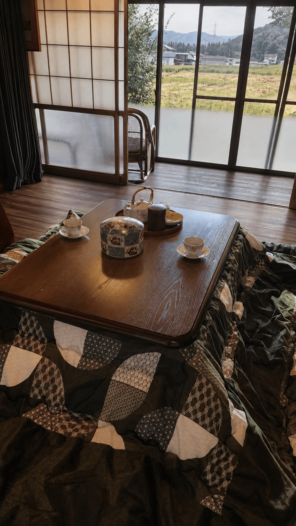 山里を望む窓辺で、茶器を載せたこたつを囲む風山舎の一室